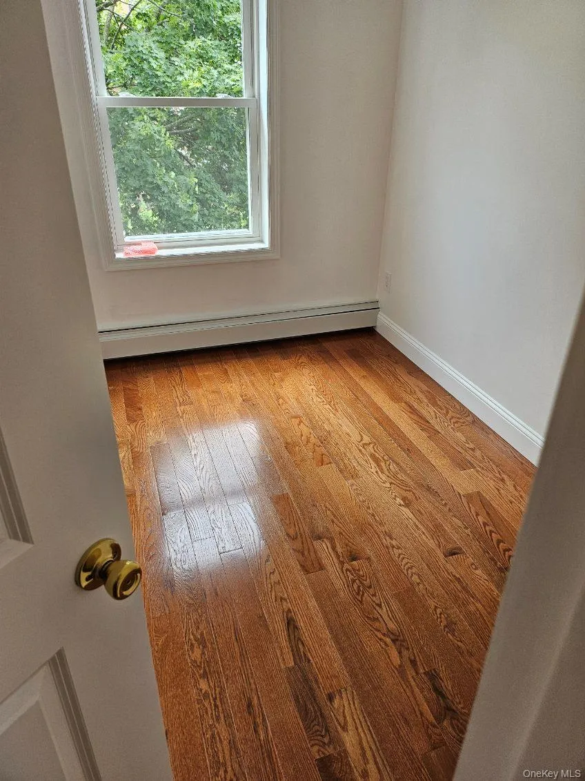 Spare room with light wood-style flooring and a baseboard heating unit Spare room with light wood-style flooring and a baseboard heating unit