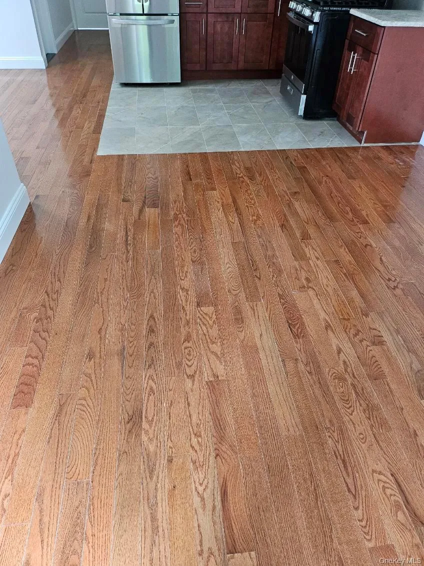 Kitchen view of light wood finished floors, stainless steel refrigerator, gas stove, and dark brown cabinetry Kitchen view of light wood finished floors, stainless steel refrigerator, gas stove, and dark brown cabinetry