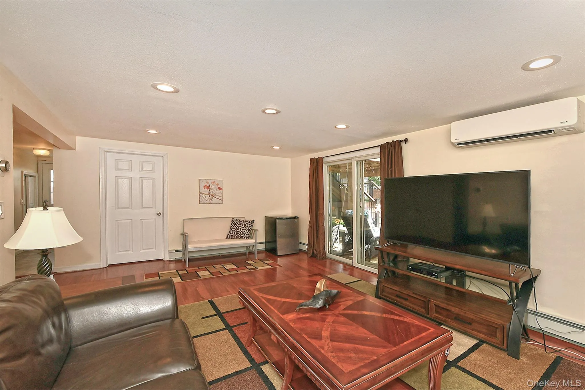 Recessed lighting, wood-finish flooring, sliding glass door, mini-split air conditioning unit, and a paneled interior door Recessed lighting, wood-finish flooring, sliding glass door, mini-split air conditioning unit, and a paneled interior door