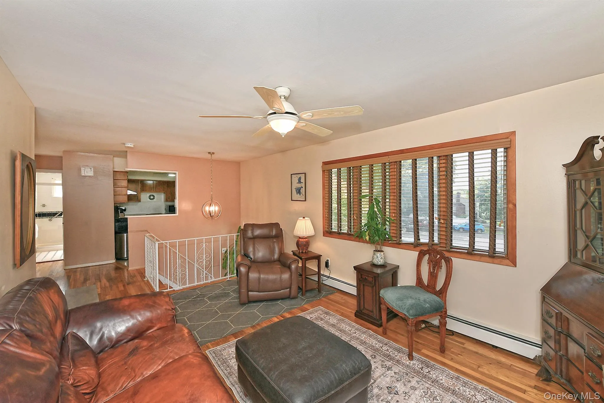 Hardwood flooring throughout, ceiling fan with integrated lighting, and a large window with wooden blinds and trim Hardwood flooring throughout, ceiling fan with integrated lighting, and a large window with wooden blinds and trim