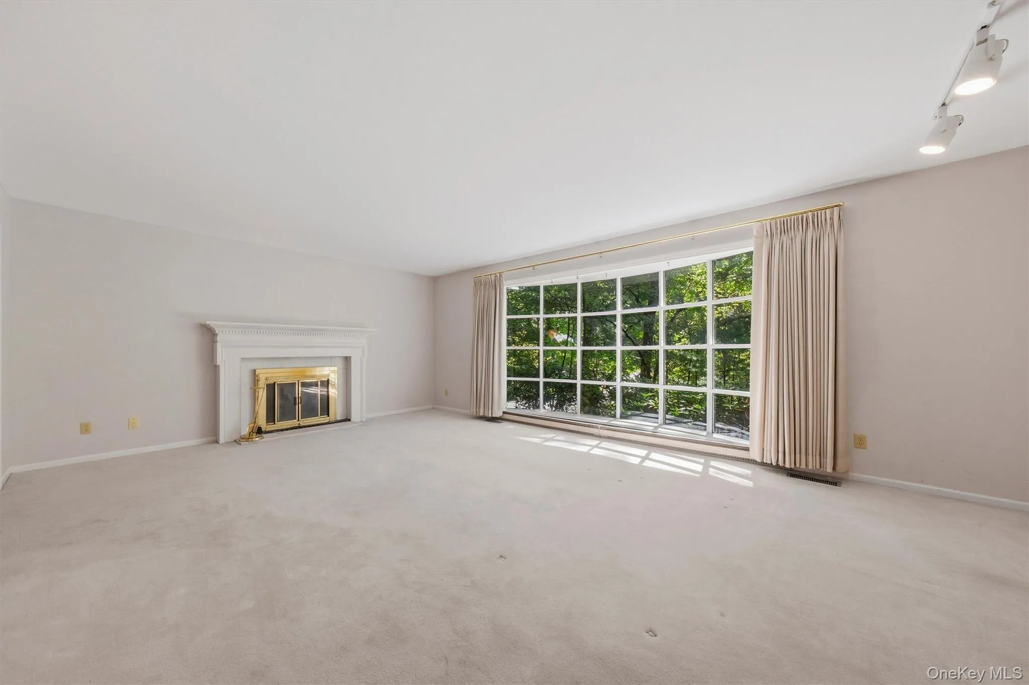 Expansive formal living room with large bow window and wood burning fireplace. Hardwood under carpet. Expansive formal living room with large bow window and wood burning fireplace. Hardwood under carpet.