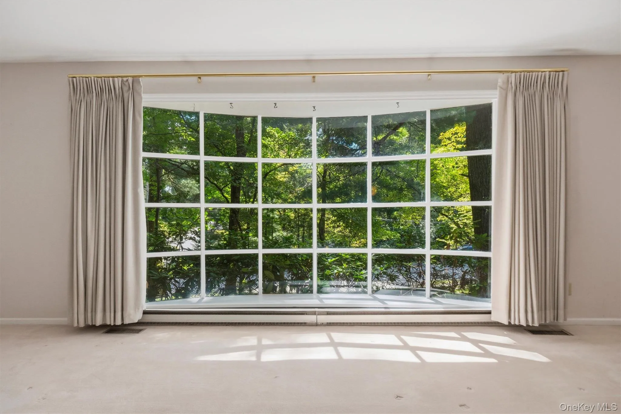 Expansive formal living room with large bow window and wood burning fireplace. Hardwood under carpet. Expansive formal living room with large bow window and wood burning fireplace. Hardwood under carpet.