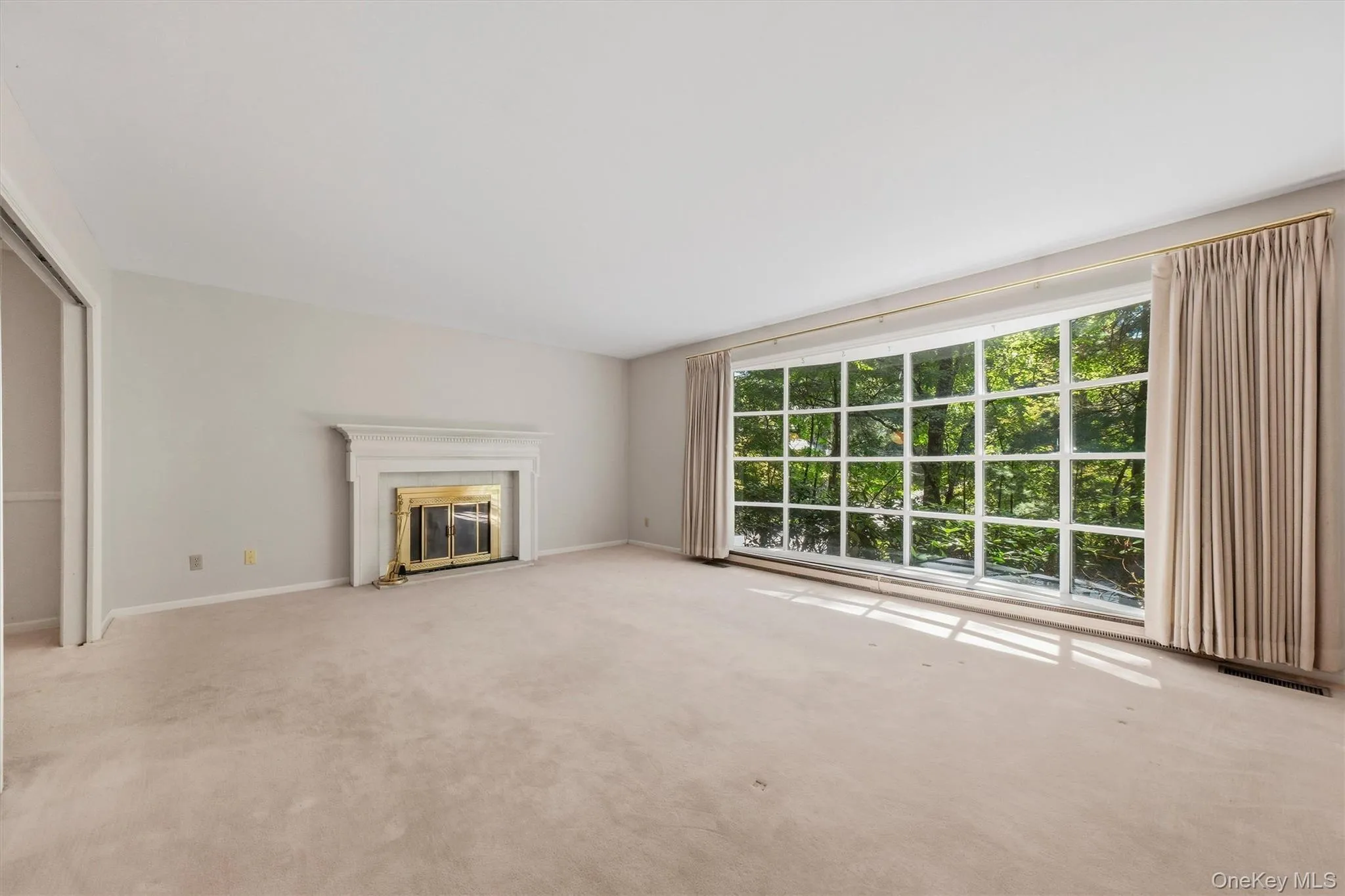 Expansive formal living room with large bow window and wood burning fireplace. Hardwood under carpet. Expansive formal living room with large bow window and wood burning fireplace. Hardwood under carpet.