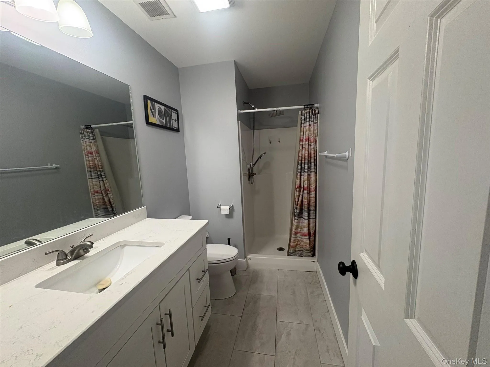 Vanity with built-in rectangular sink, light-toned countertop, and white cabinetry with dark hardware Vanity with built-in rectangular sink, light-toned countertop, and white cabinetry with dark hardware