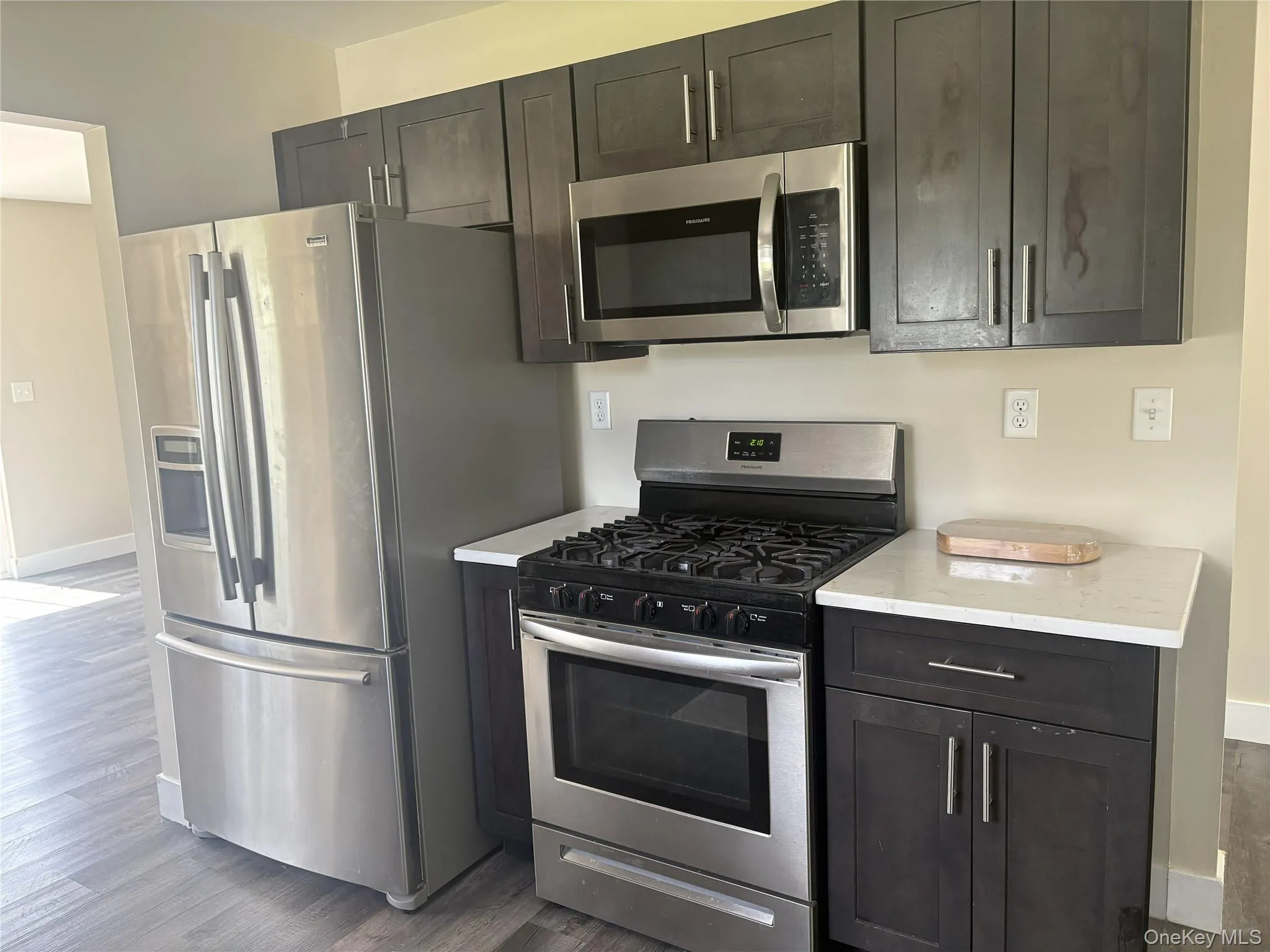 Stainless steel appliances, dark wood-finish cabinetry, white countertops, wood-finish flooring Stainless steel appliances, dark wood-finish cabinetry, white countertops, wood-finish flooring