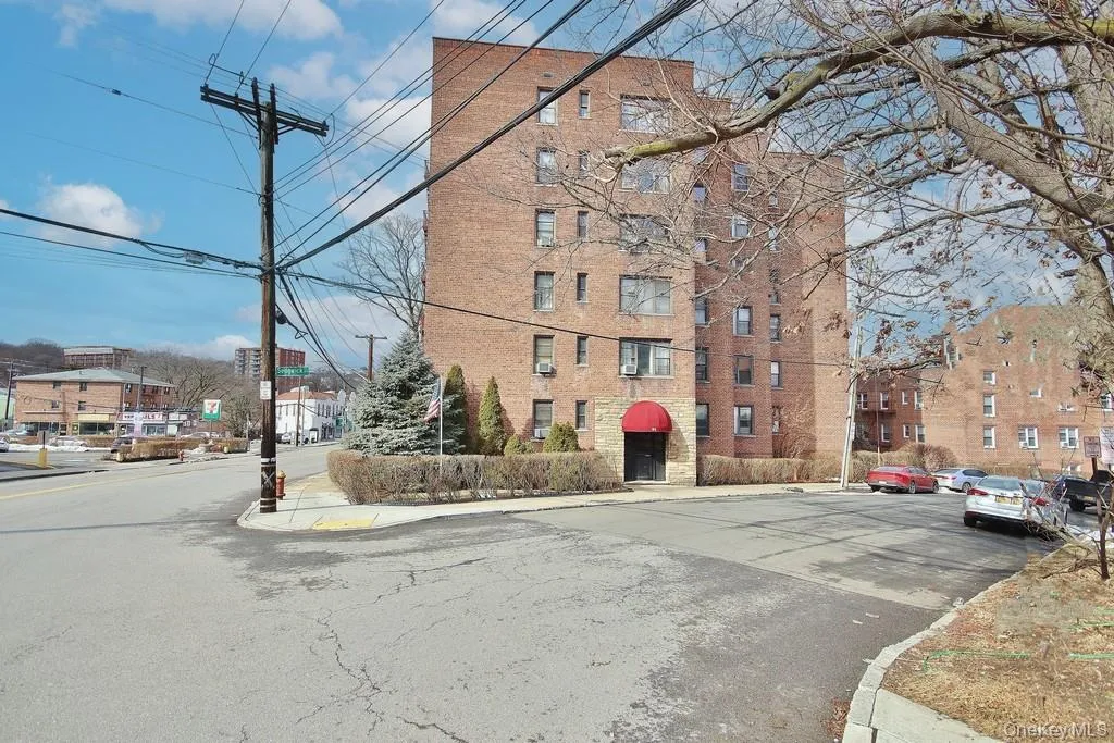 Brick facade residential building with multiple stories, featuring a prominent red awning over the main entrance Brick facade residential building with multiple stories, featuring a prominent red awning over the main entrance