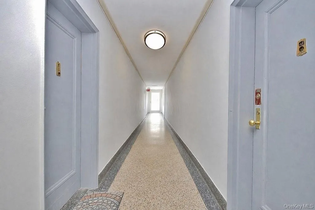 Long hallway with light gray doors and a terrazzo-style floor Long hallway with light gray doors and a terrazzo-style floor