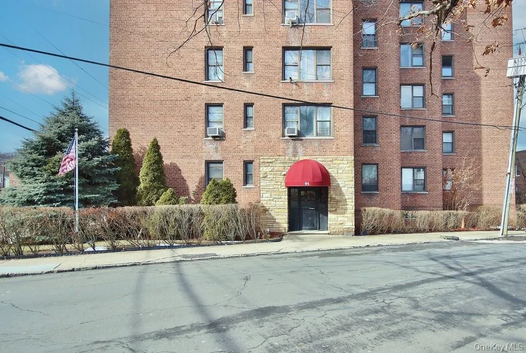 Brick exterior building with multiple windows, a red awning, and stone facade entrance Brick exterior building with multiple windows, a red awning, and stone facade entrance