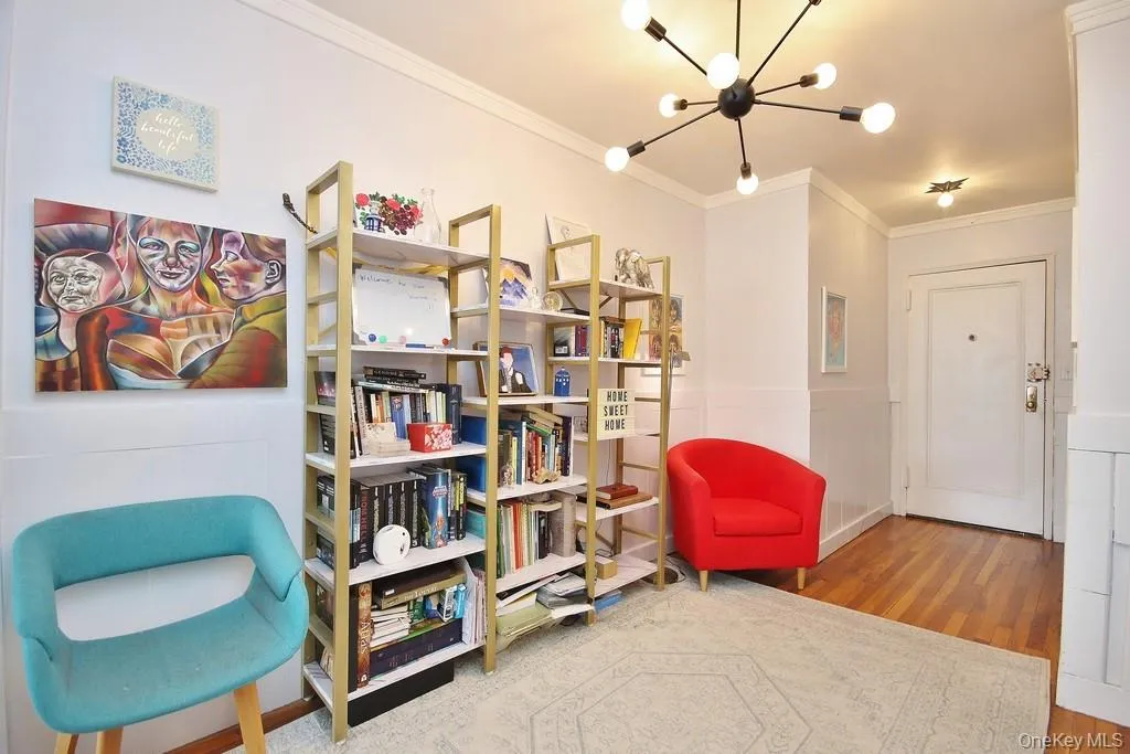 Hardwood flooring, crown molding, a built-in shelving unit, a paneled door, and a modern chandelier Hardwood flooring, crown molding, a built-in shelving unit, a paneled door, and a modern chandelier