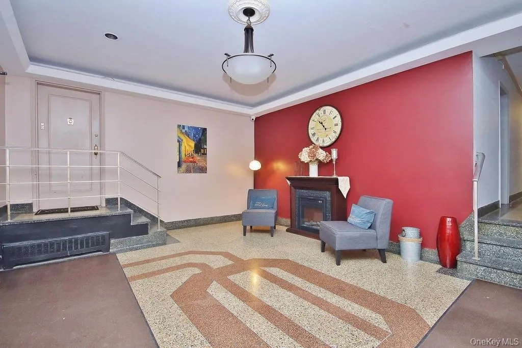 Terrazzo flooring with geometric inlay, decorative fireplace with mantel, and a classic ceiling light fixture Terrazzo flooring with geometric inlay, decorative fireplace with mantel, and a classic ceiling light fixture