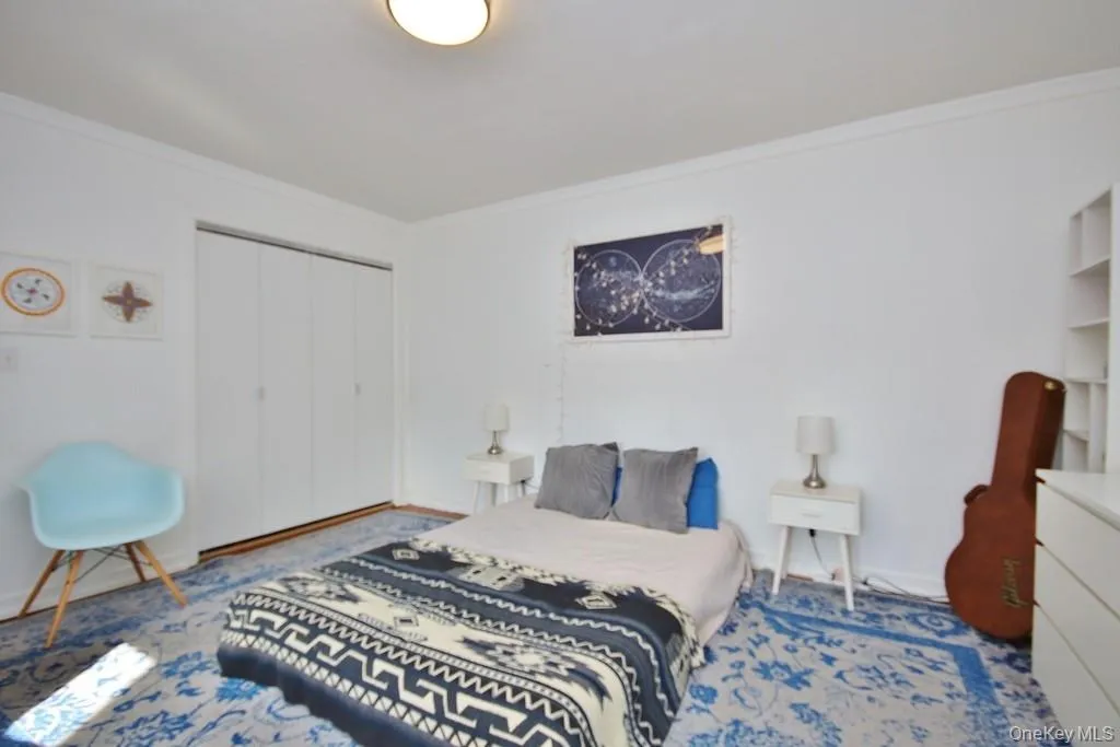White walls with crown molding, wood-finish flooring, and built-in closet with bi-fold doors White walls with crown molding, wood-finish flooring, and built-in closet with bi-fold doors