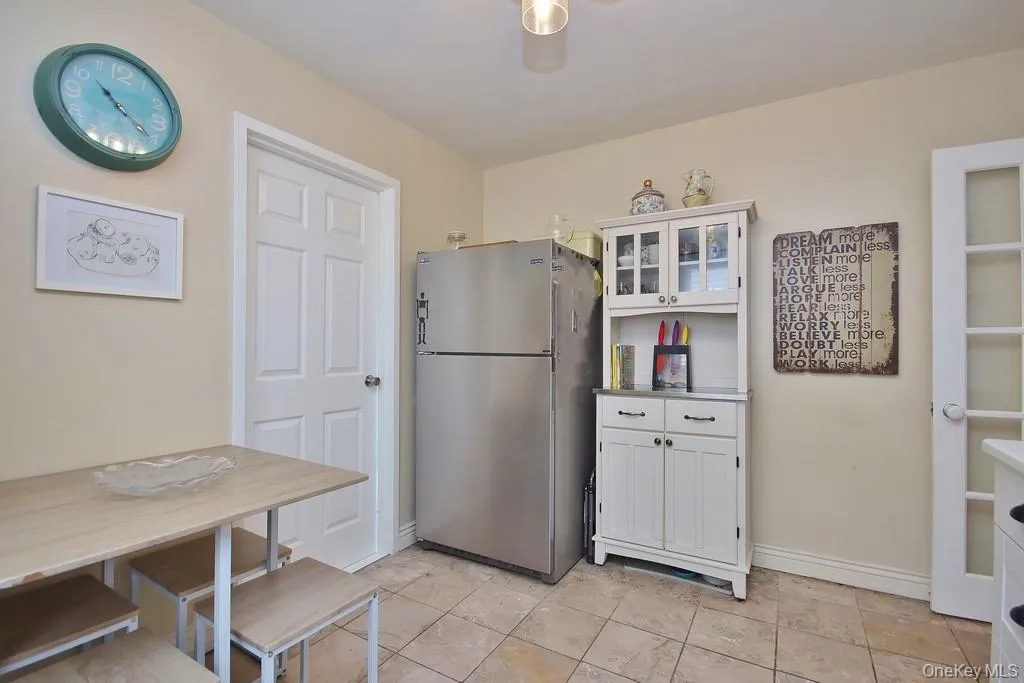 Tile flooring, white paneled interior door, stainless steel refrigerator, white hutch with glass-front upper cabinetry, French doors with frosted glass Tile flooring, white paneled interior door, stainless steel refrigerator, white hutch with glass-front upper cabinetry, French doors with frosted glass