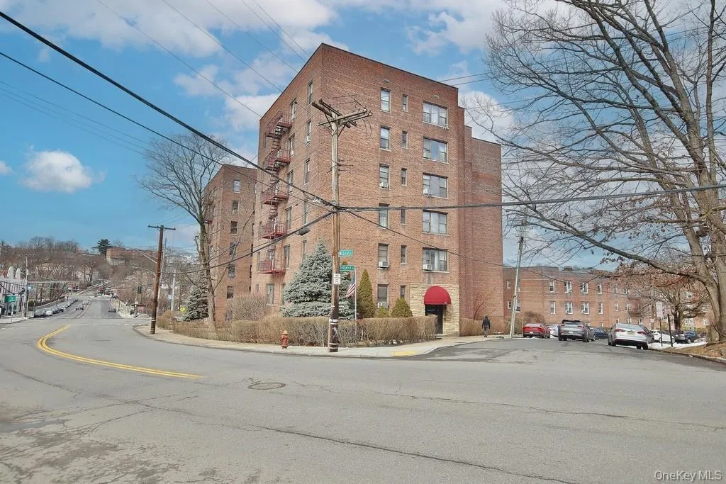 Brick facade building with multiple stories, a red entrance awning, and mature landscaping Brick facade building with multiple stories, a red entrance awning, and mature landscaping