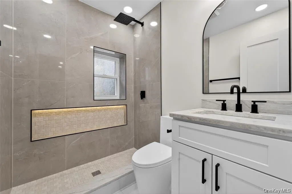 Porcelain tile shower with a built-in recessed niche, rainfall showerhead, and window Porcelain tile shower with a built-in recessed niche, rainfall showerhead, and window
