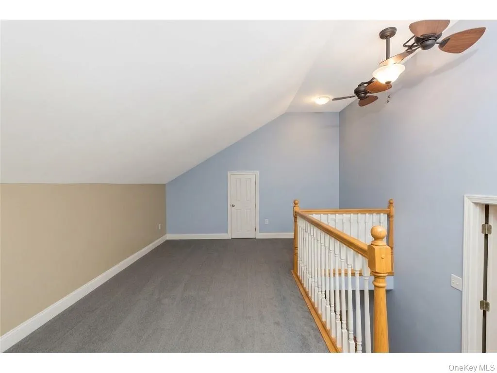Sloped ceiling room with recessed lighting, ceiling fan, carpeted flooring, and a spindle wood railing Sloped ceiling room with recessed lighting, ceiling fan, carpeted flooring, and a spindle wood railing