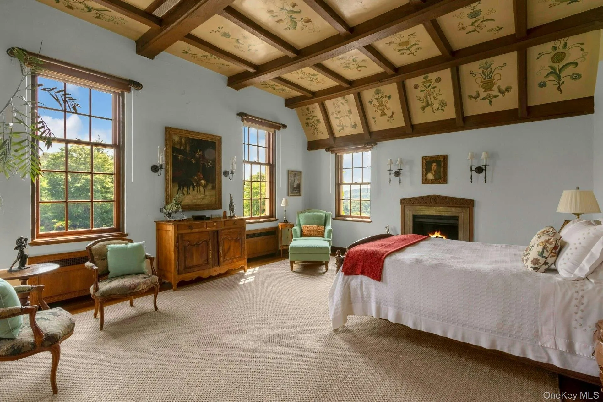 Carpeted bedroom with beamed ceiling and a warm lit fireplace Carpeted bedroom with beamed ceiling and a warm lit fireplace