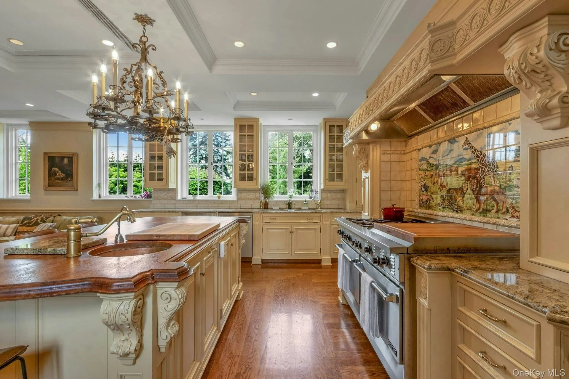 Kitchen featuring ornamental molding, wood finished floors, glass insert cabinets, cream cabinets, and decorative backsplash Kitchen featuring ornamental molding, wood finished floors, glass insert cabinets, cream cabinets, and decorative backsplash