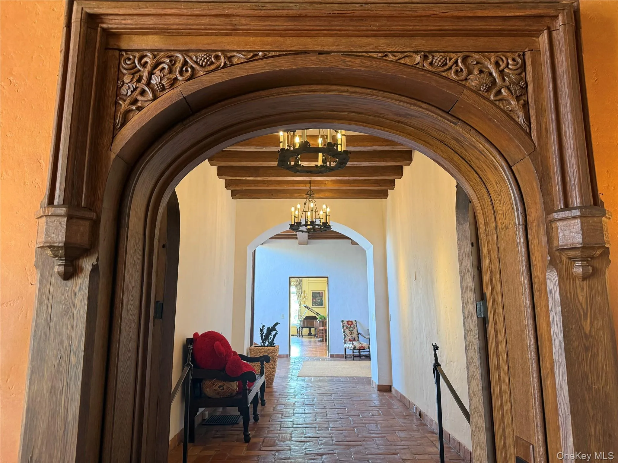 Hall with a chandelier, beam ceiling, a textured wall, and arched walkways Hall with a chandelier, beam ceiling, a textured wall, and arched walkways