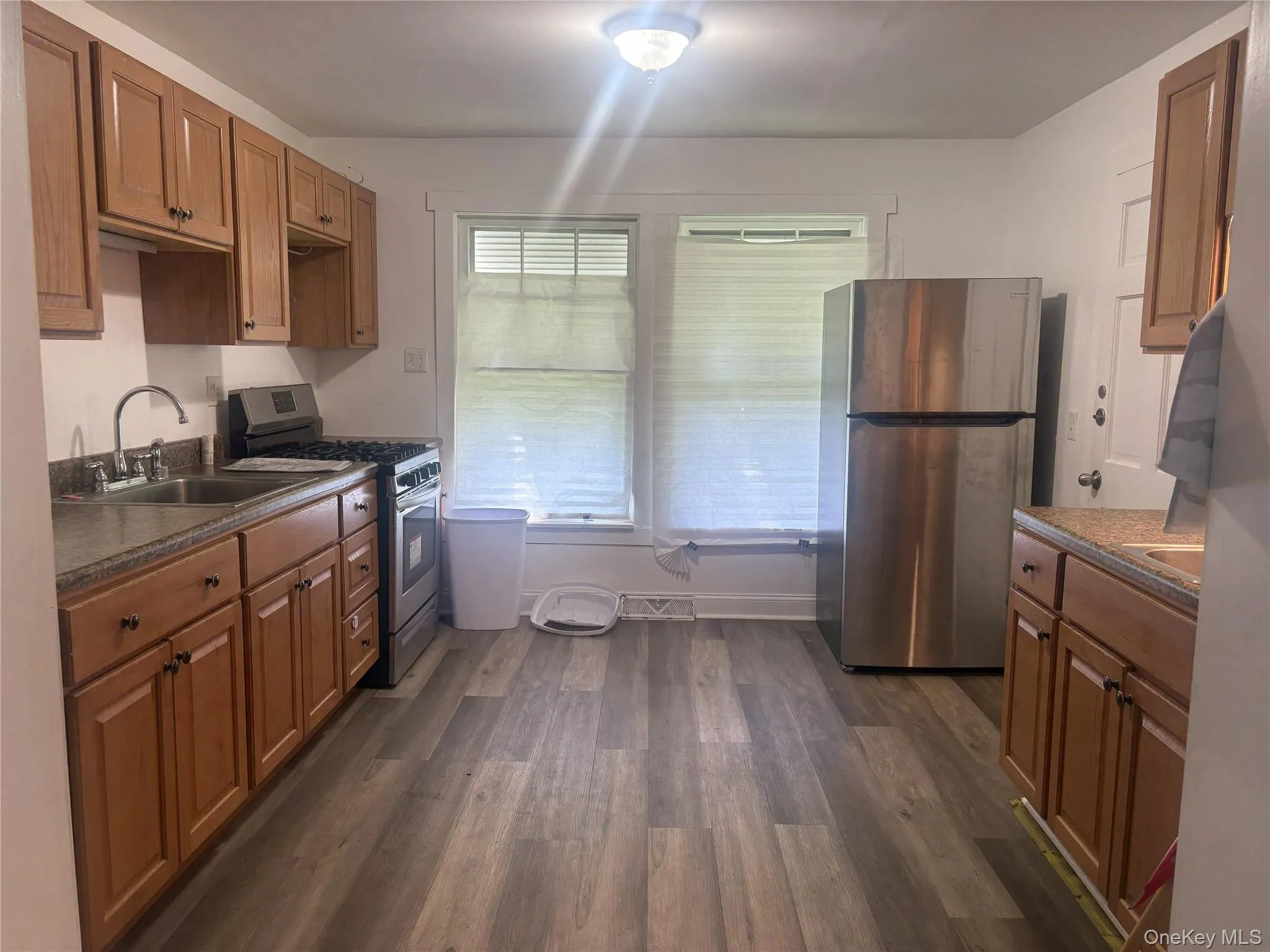 Kitchen featuring wood-finish flooring, wood cabinetry, a stainless steel refrigerator, and a stainless steel range Kitchen featuring wood-finish flooring, wood cabinetry, a stainless steel refrigerator, and a stainless steel range