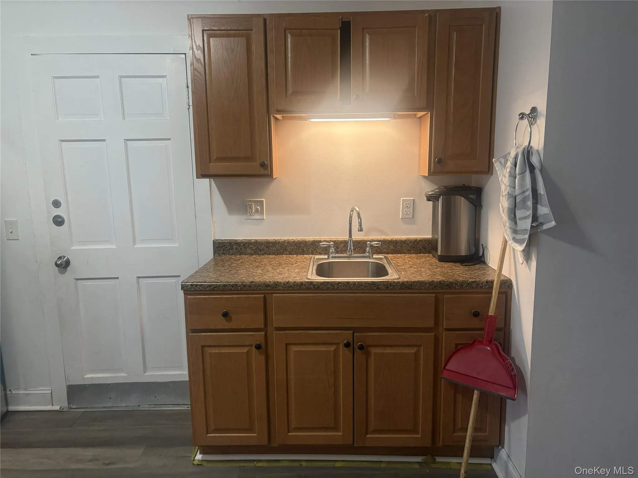 Kitchenette featuring wood cabinetry, laminate countertops, stainless steel sink, and wood-finish flooring Kitchenette featuring wood cabinetry, laminate countertops, stainless steel sink, and wood-finish flooring