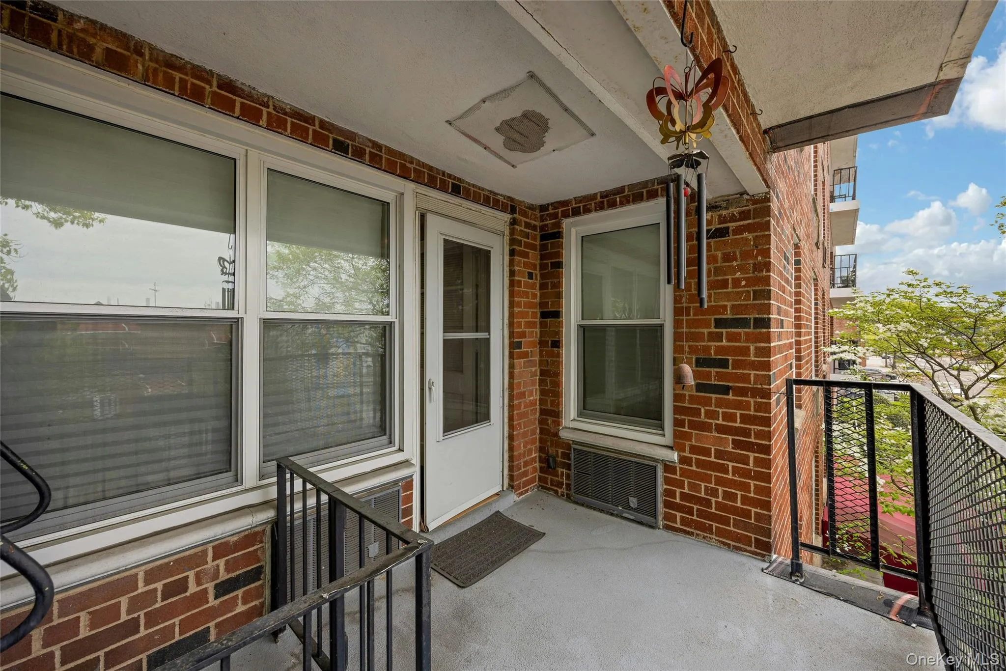 Private balcony featuring brick exterior, white-framed windows, and metal railings Private balcony featuring brick exterior, white-framed windows, and metal railings