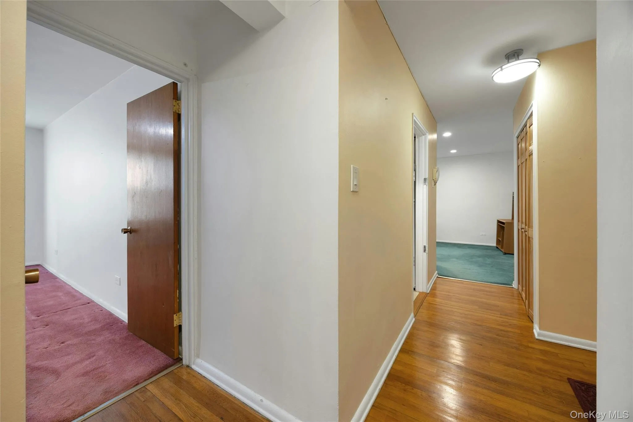 Hallway featuring wood-finish flooring, light-toned wall paint, and a semi-flush mount ceiling light Hallway featuring wood-finish flooring, light-toned wall paint, and a semi-flush mount ceiling light