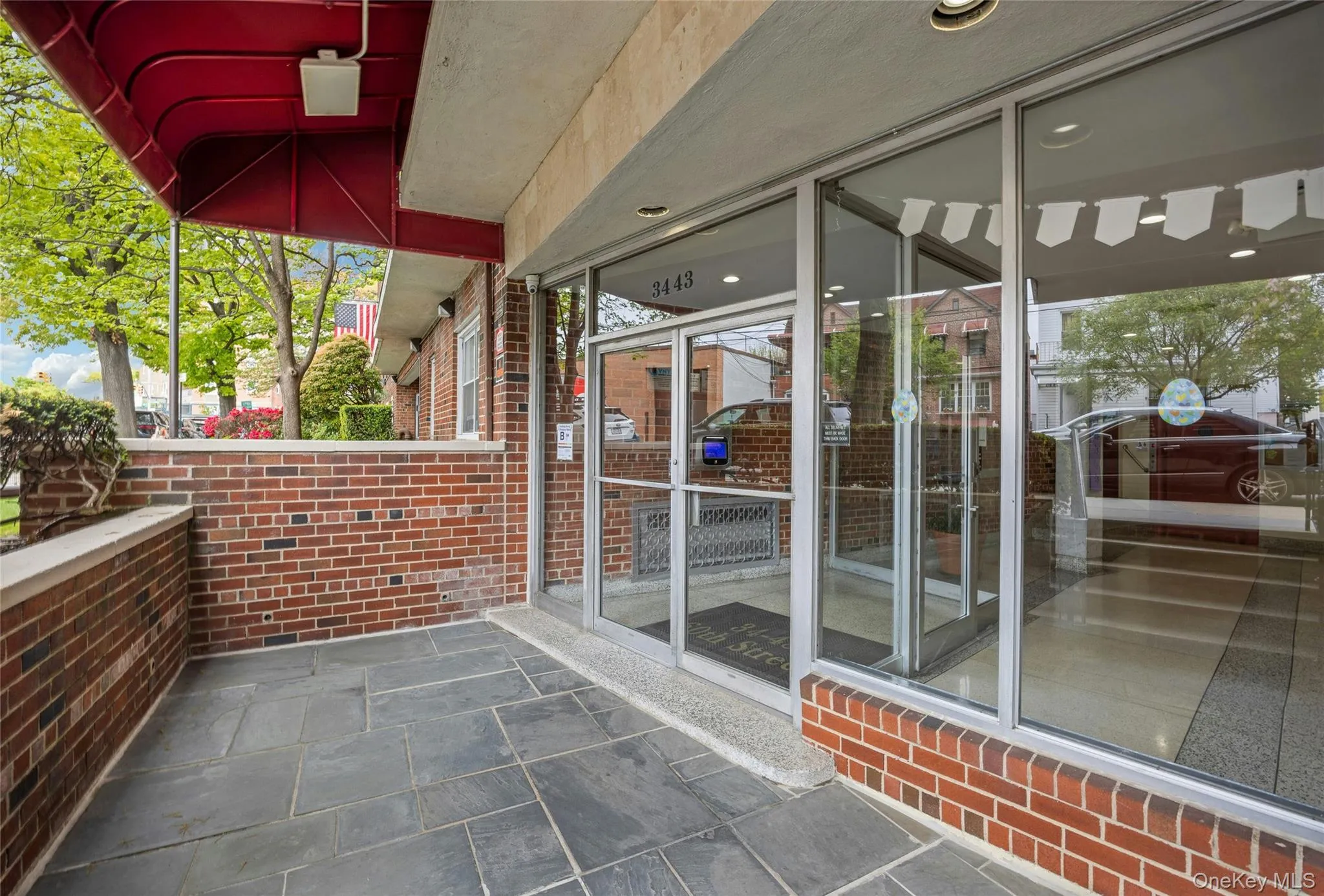 Brick facade entry with a red awning, slate tile landing, and a glass-paneled entry door Brick facade entry with a red awning, slate tile landing, and a glass-paneled entry door