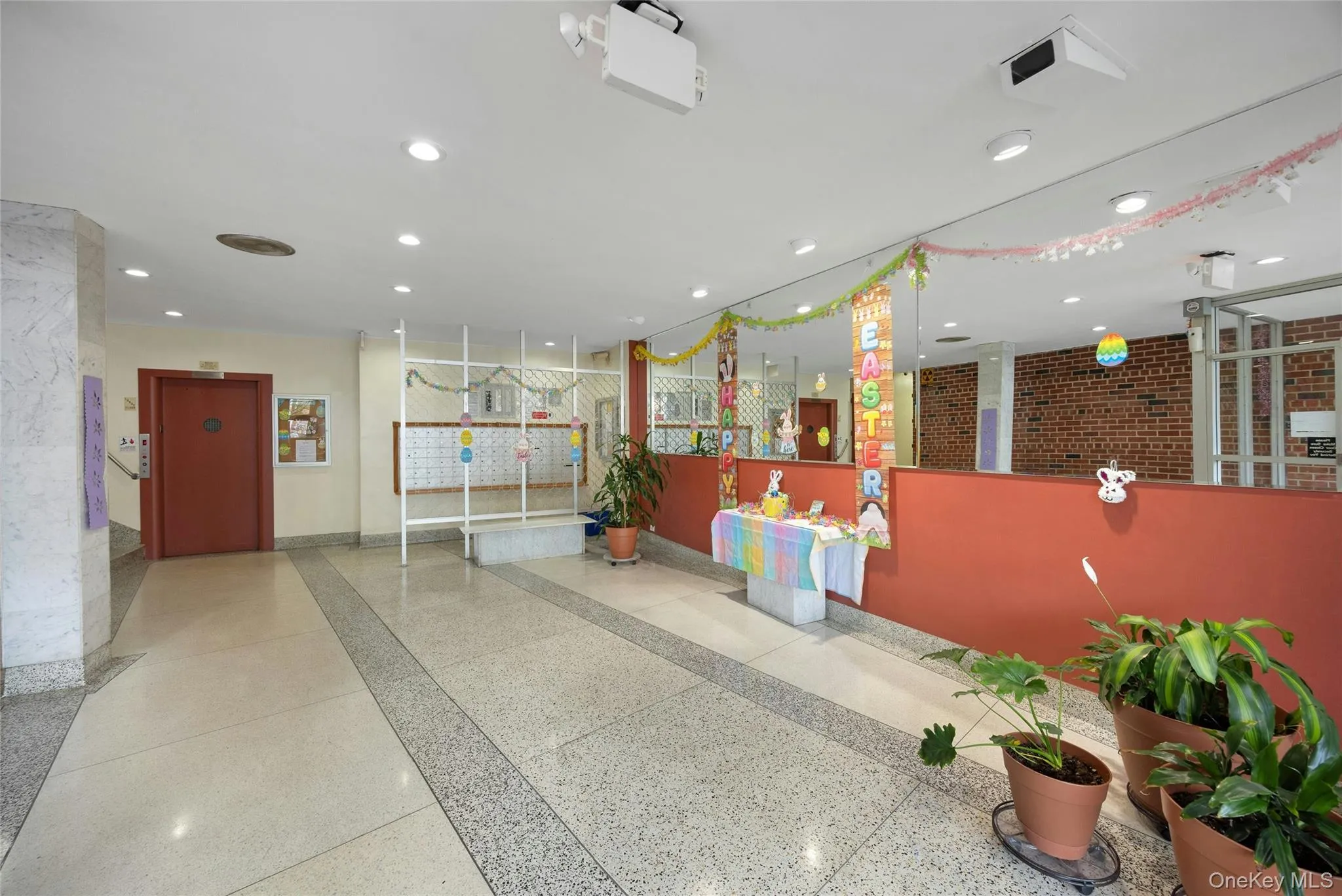 Spacious communal area featuring terrazzo flooring, recessed lighting, brick accent walls, and a large mirrored wall Spacious communal area featuring terrazzo flooring, recessed lighting, brick accent walls, and a large mirrored wall