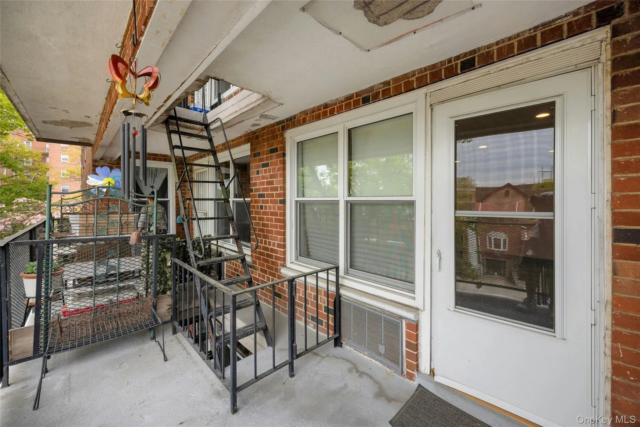 Exterior balcony access featuring a white door with a window, white-framed windows, and red brick siding Exterior balcony access featuring a white door with a window, white-framed windows, and red brick siding