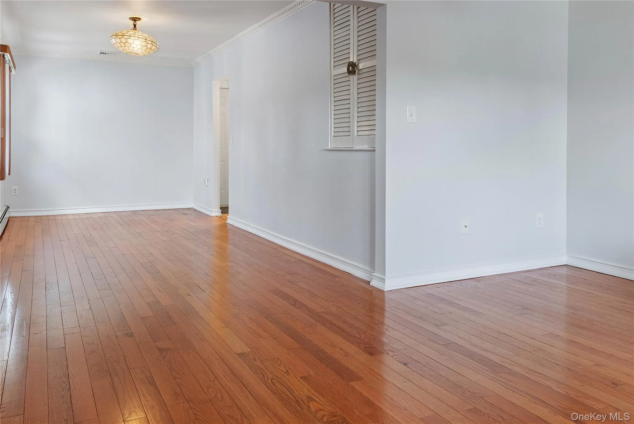 Formal Living Room and Dining Room with Hardwood flooring, crown molding, and a decorative semi-flush mount light fixture Formal Living Room and Dining Room with Hardwood flooring, crown molding, and a decorative semi-flush mount light fixture