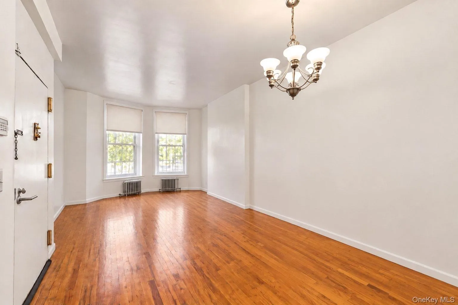Hardwood flooring throughout, with a bay window feature, two double-hung windows, and a multi-arm chandelier Hardwood flooring throughout, with a bay window feature, two double-hung windows, and a multi-arm chandelier