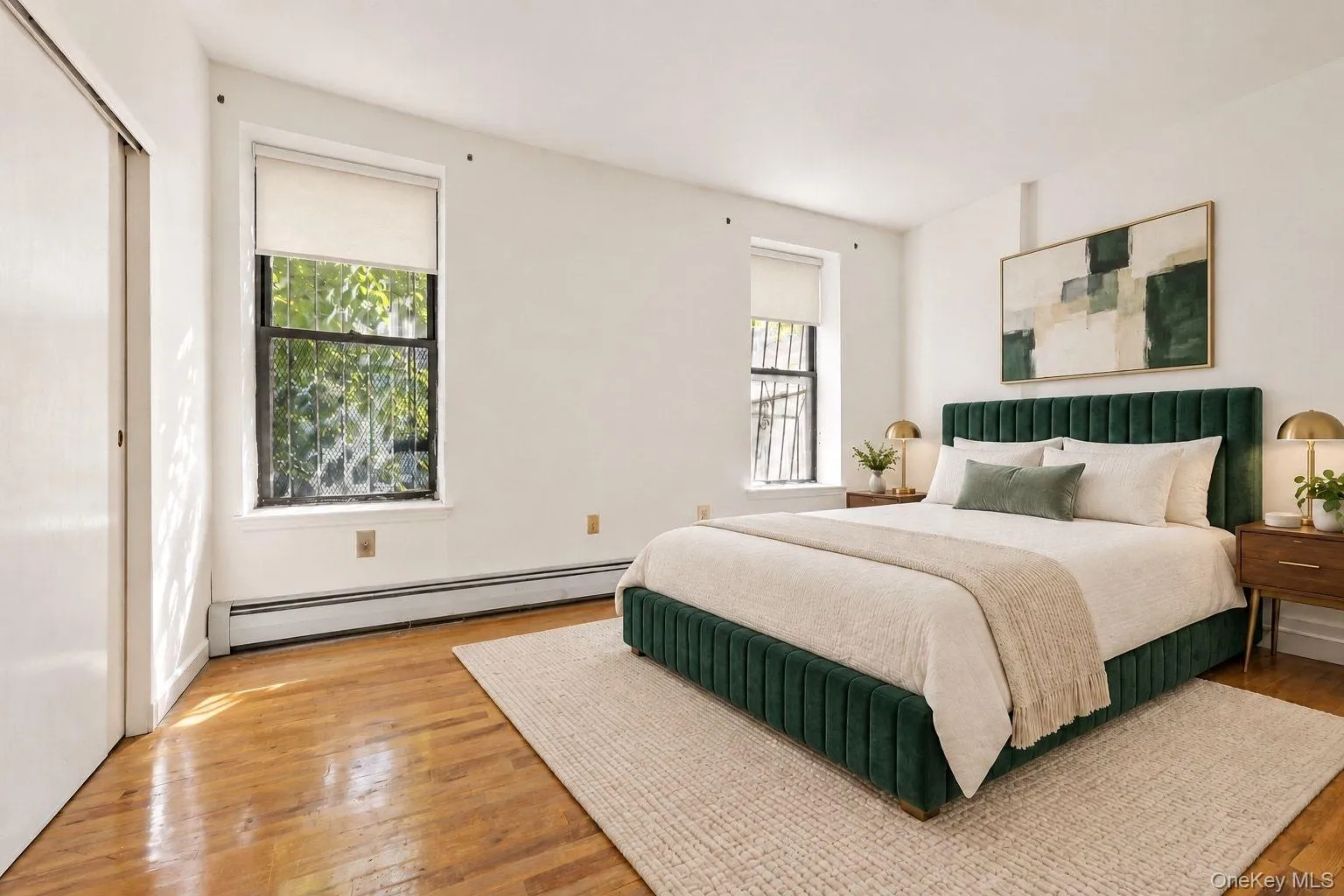 Hardwood flooring, painted white walls, two windows with roller shades, and a built-in closet with sliding doors Hardwood flooring, painted white walls, two windows with roller shades, and a built-in closet with sliding doors