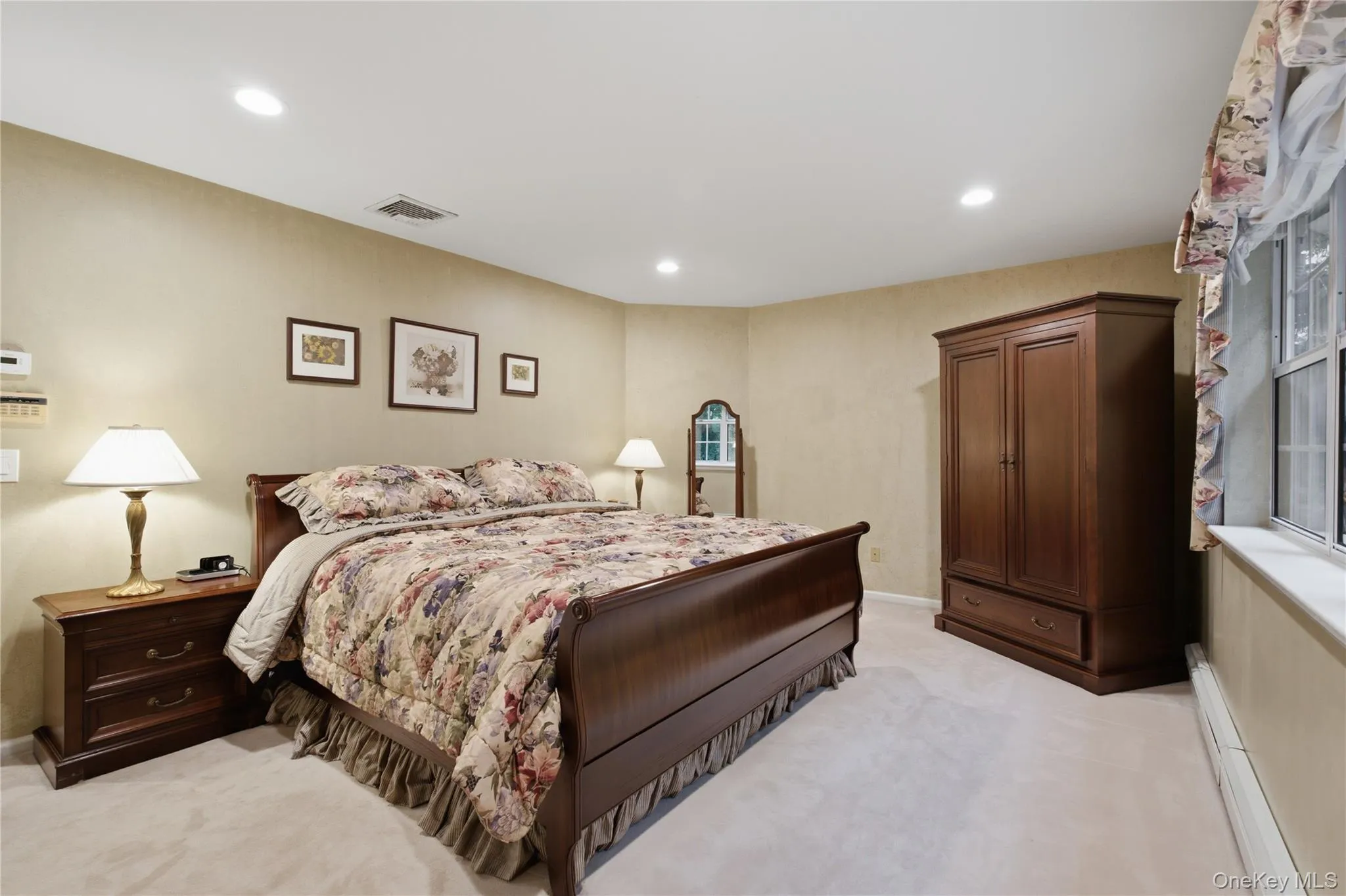 Spacious and gracious Primary Bedroom Overlooking the Peaceful Backdrop of Mature Trees, with Hardwood Flooring Beneath the Existing Carpeting. Spacious and gracious Primary Bedroom Overlooking the Peaceful Backdrop of Mature Trees, with Hardwood Flooring Beneath the Existing Carpeting.