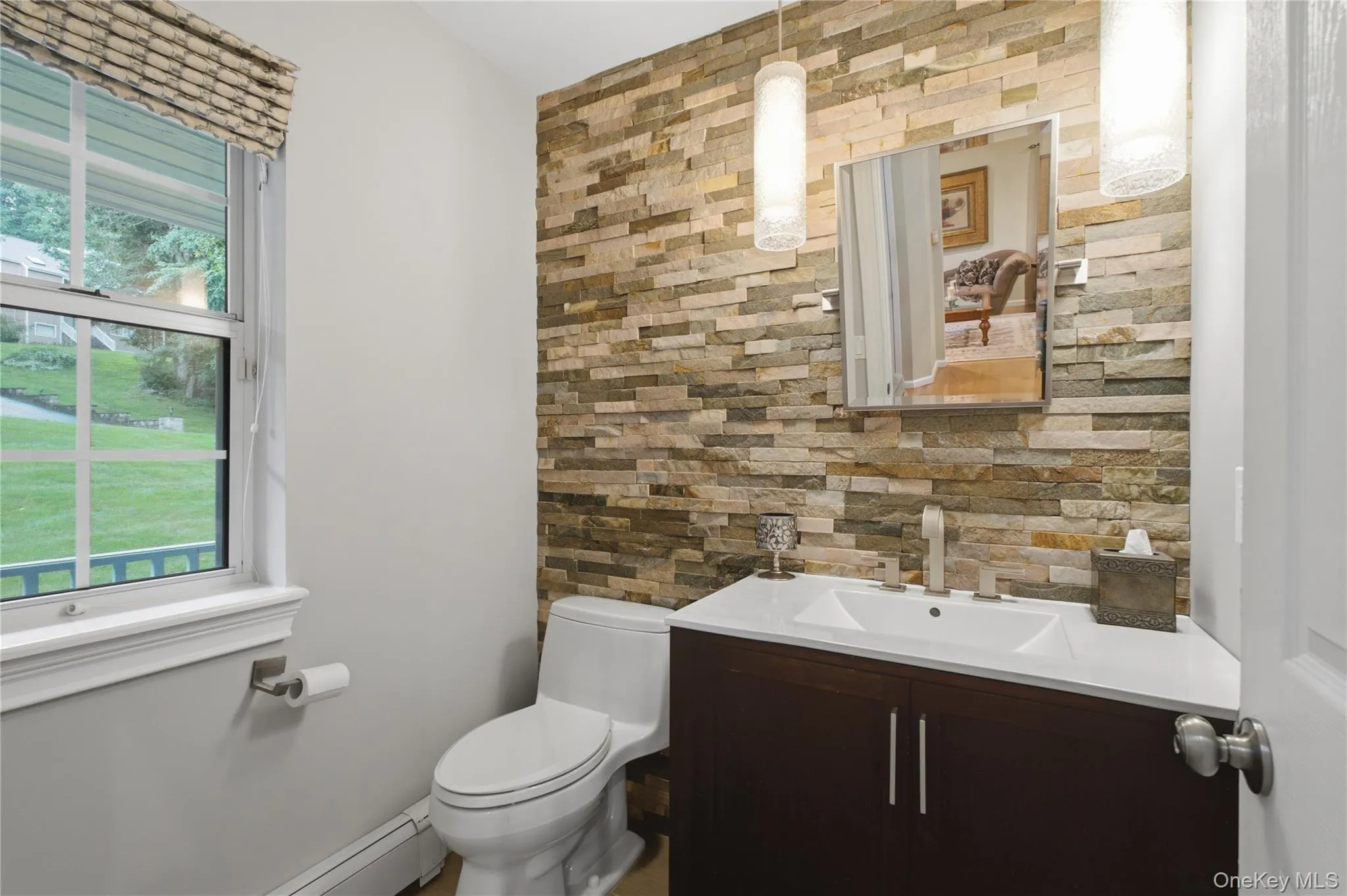 Beautifully Updated, Windowed Powder Room with a Distinctive Stone-Accented Wall—Conveniently Located for Guests While Thoughtfully Tucked Away for Privacy. Beautifully Updated, Windowed Powder Room with a Distinctive Stone-Accented Wall—Conveniently Located for Guests While Thoughtfully Tucked Away for Privacy.