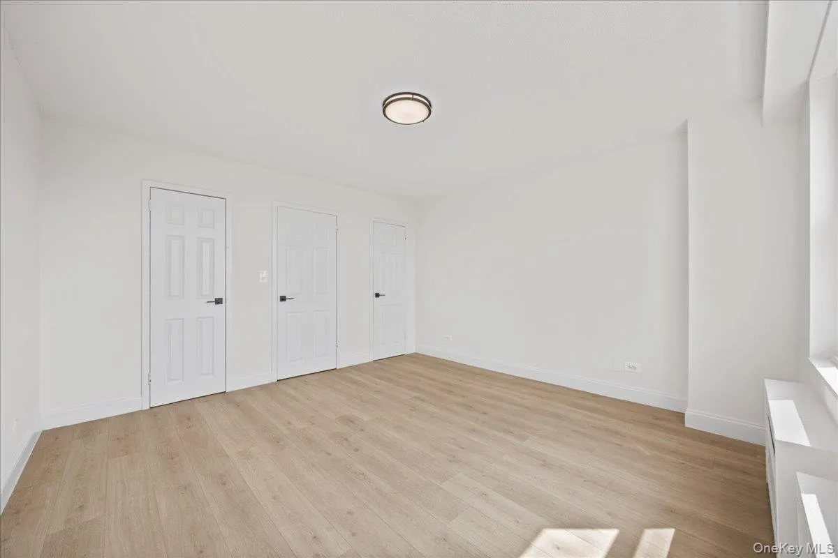 Vinyl flooring, white paneled doors, ceiling-mounted lighting, and a window with a sill Vinyl flooring, white paneled doors, ceiling-mounted lighting, and a window with a sill