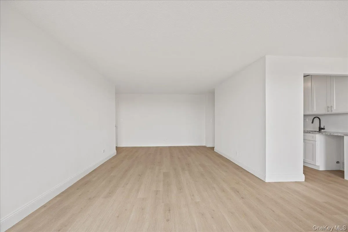 Spacious interior with neutral white walls, vinyl flooring, and ample natural light from a large window Spacious interior with neutral white walls, vinyl flooring, and ample natural light from a large window