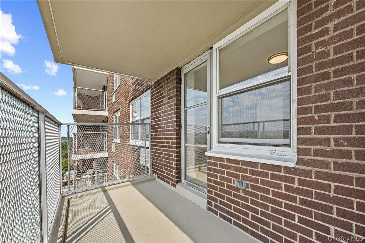 Balcony with concrete flooring, brick exterior, metal mesh railing, and exterior lighting Balcony with concrete flooring, brick exterior, metal mesh railing, and exterior lighting