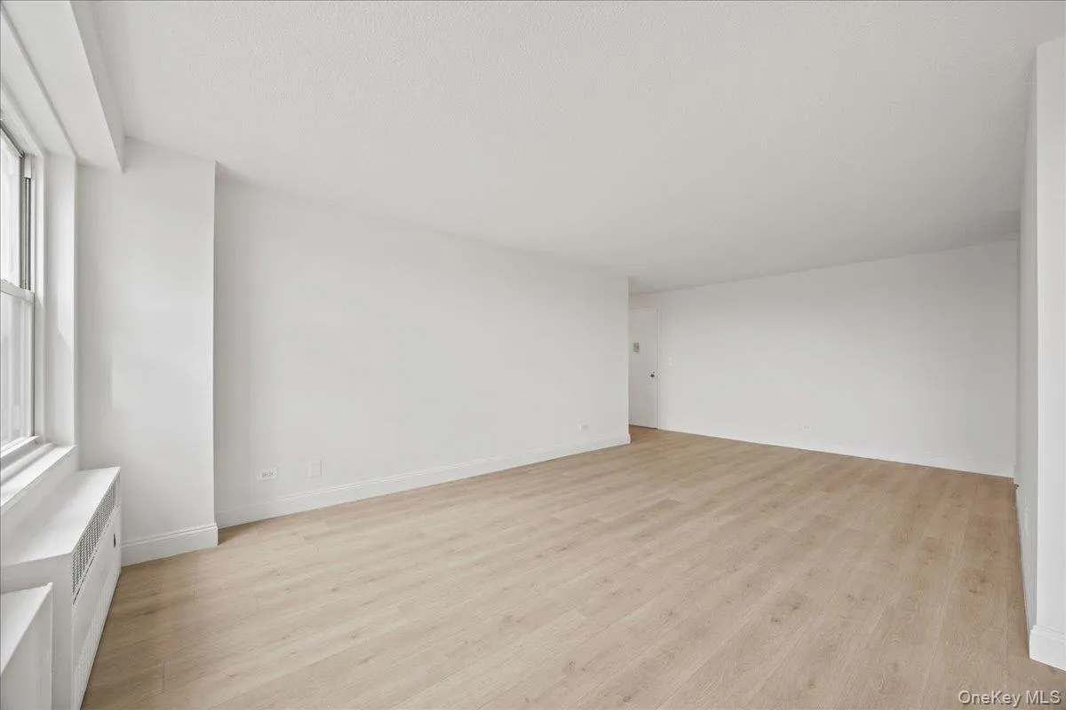 Spacious interior with neutral white walls, vinyl flooring, and ample natural light from a large window Spacious interior with neutral white walls, vinyl flooring, and ample natural light from a large window
