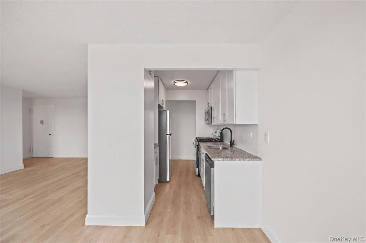 White cabinetry, stainless steel appliances, vinyl flooring, a contemporary black faucet, and stone countertops White cabinetry, stainless steel appliances, vinyl flooring, a contemporary black faucet, and stone countertops