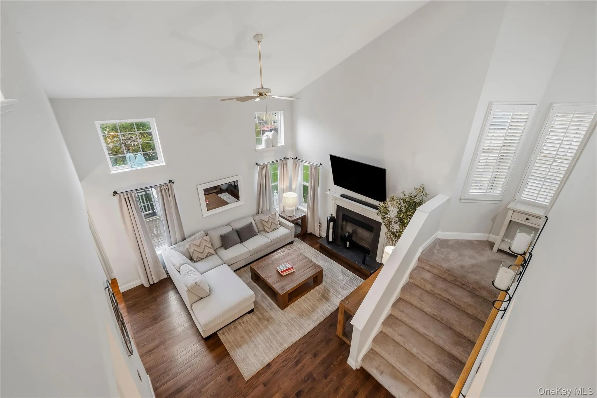 Vaulted ceiling living space with wood-finish flooring, a fireplace, and multiple windows Vaulted ceiling living space with wood-finish flooring, a fireplace, and multiple windows