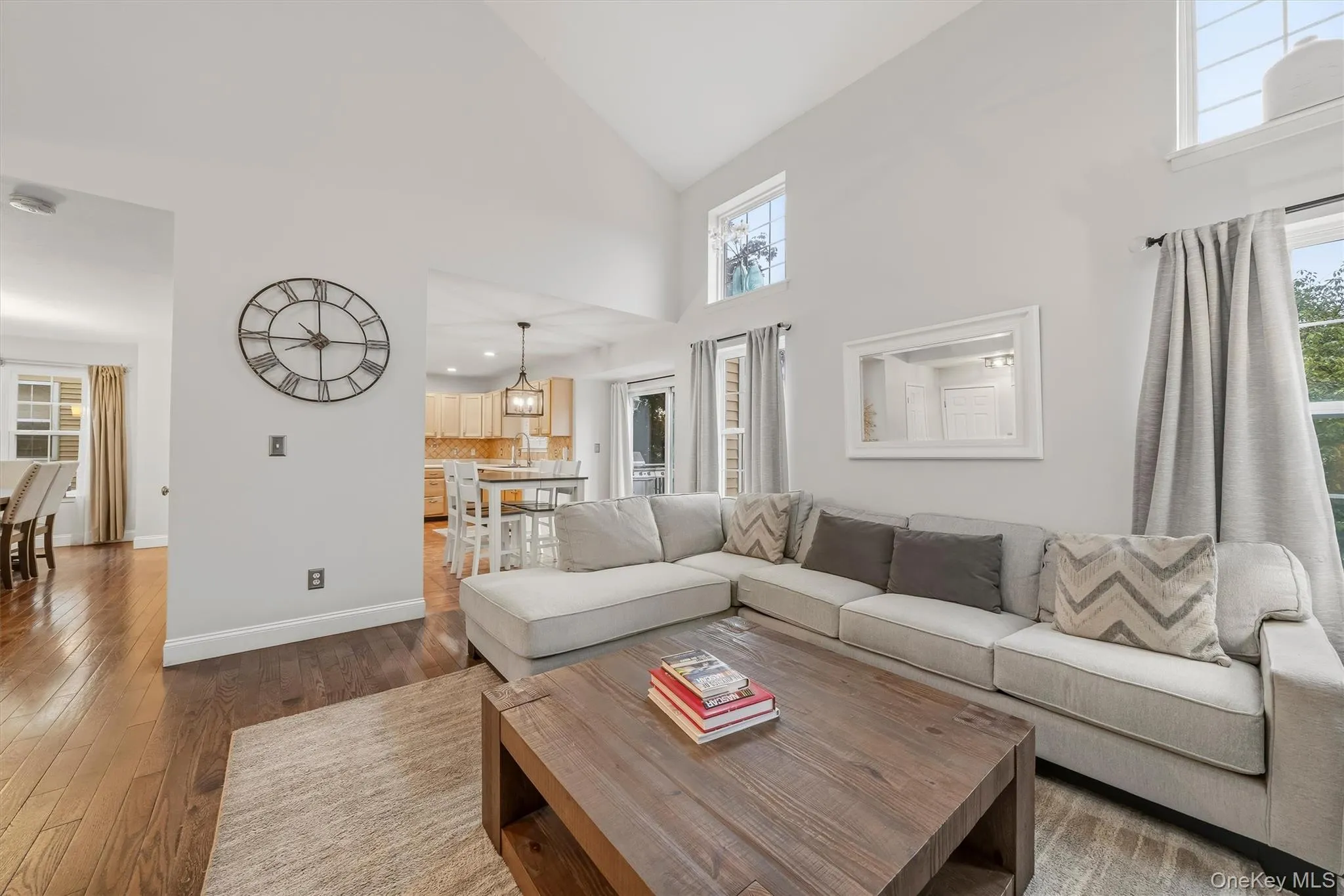 Vaulted ceilings with high windows, wood-finish flooring, a kitchen with wood cabinetry, and a dining area Vaulted ceilings with high windows, wood-finish flooring, a kitchen with wood cabinetry, and a dining area