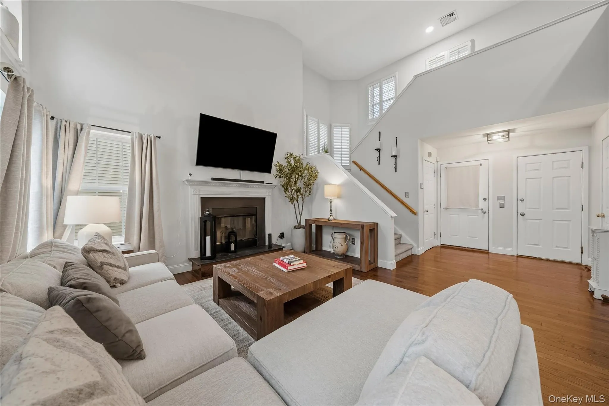 Vaulted ceiling, hardwood flooring, fireplace, white trim, and a built-in staircase Vaulted ceiling, hardwood flooring, fireplace, white trim, and a built-in staircase