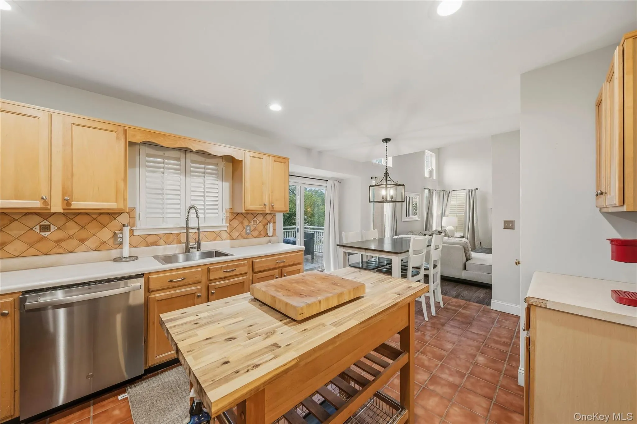 Kitchen featuring wood cabinetry, stainless steel dishwasher and terracotta-style floor tiles Kitchen featuring wood cabinetry, stainless steel dishwasher and terracotta-style floor tiles