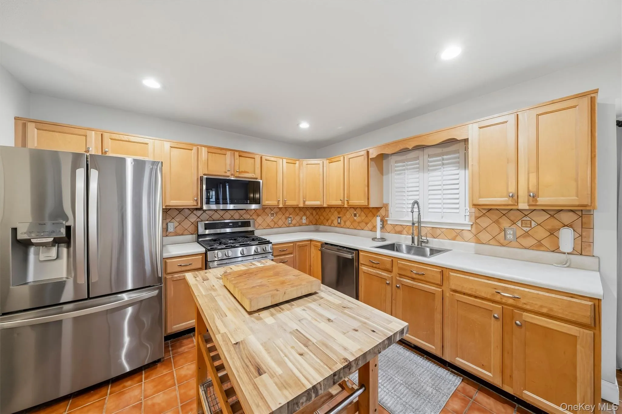 Kitchen featuring wood cabinetry, stainless steel appliances and a tiled backsplash Kitchen featuring wood cabinetry, stainless steel appliances and a tiled backsplash