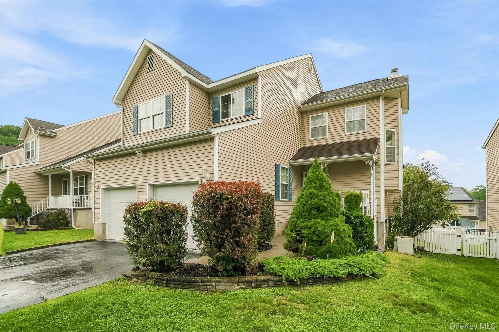 Corner view of two story home-established landscaping, and a white picket fence Corner view of two story home-established landscaping, and a white picket fence