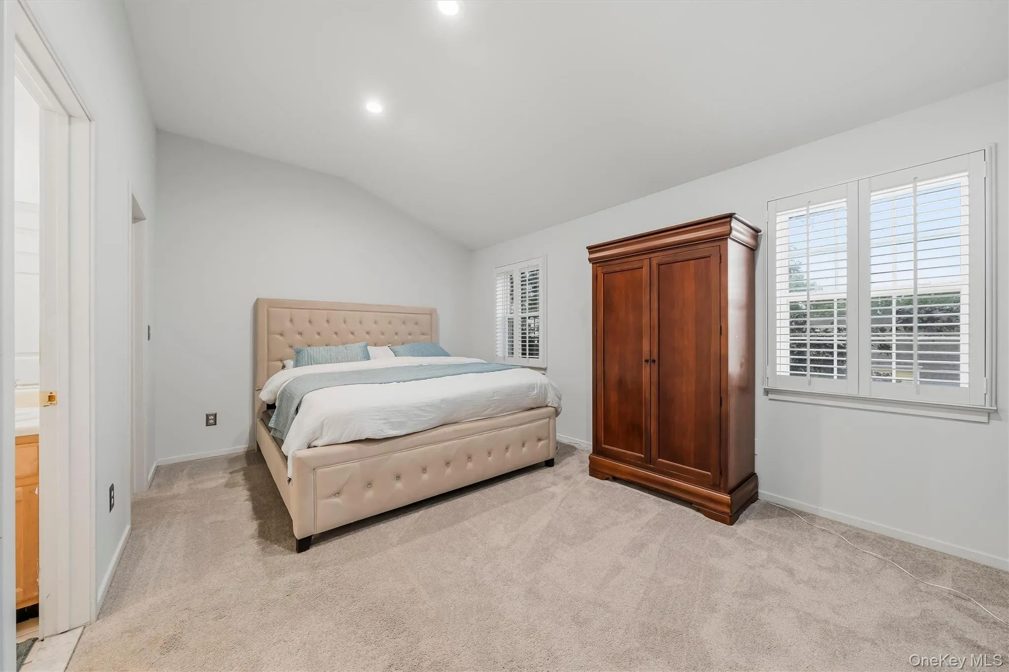 Vaulted ceiling, recessed lighting, neutral wall tones, plantation shutters, and light-toned carpeting Vaulted ceiling, recessed lighting, neutral wall tones, plantation shutters, and light-toned carpeting