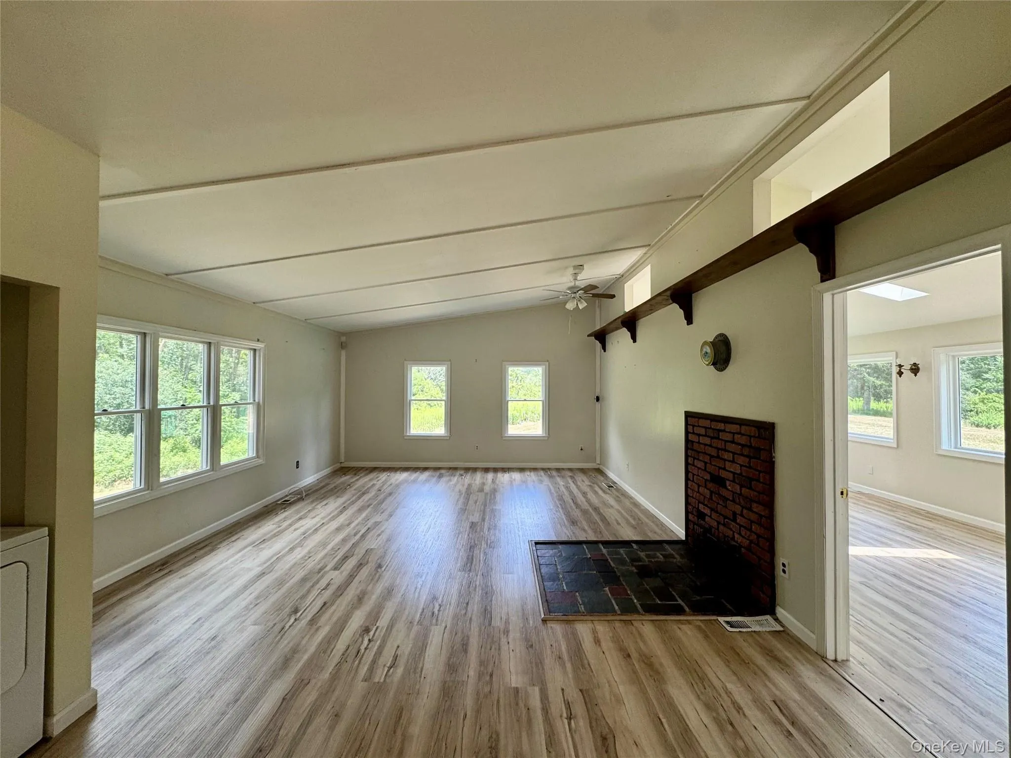 Living room featuring wood finished floors, plenty of natural light, ceiling fan, and washer / clothes dryer Living room featuring wood finished floors, plenty of natural light, ceiling fan, and washer / clothes dryer