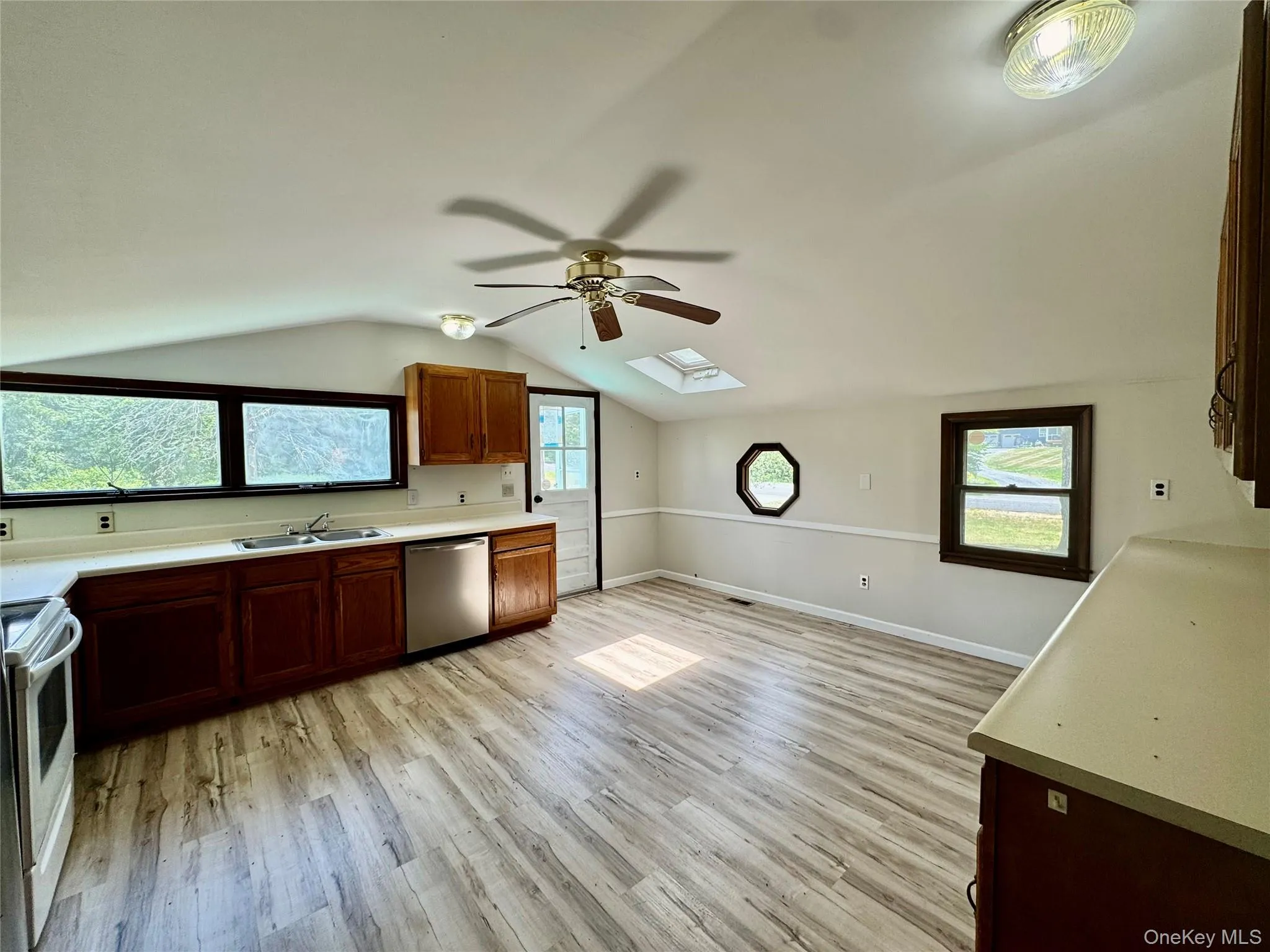 Kitchen with a skylight, a ceiling fan, light wood-style flooring, electric stove, and lofted ceiling Kitchen with a skylight, a ceiling fan, light wood-style flooring, electric stove, and lofted ceiling