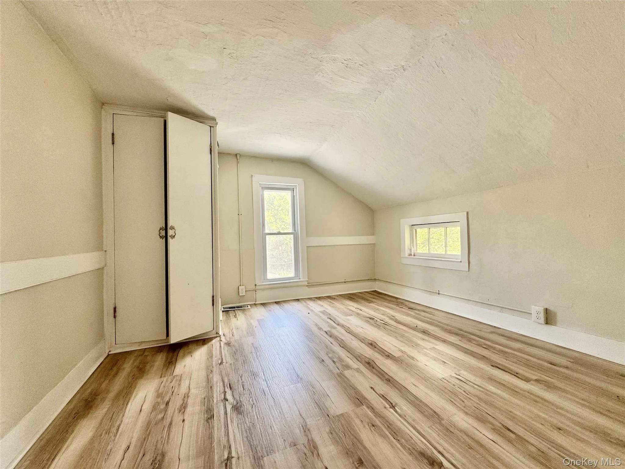 Bedroom with a textured ceiling, wood finished floors, and vaulted ceiling Bedroom with a textured ceiling, wood finished floors, and vaulted ceiling