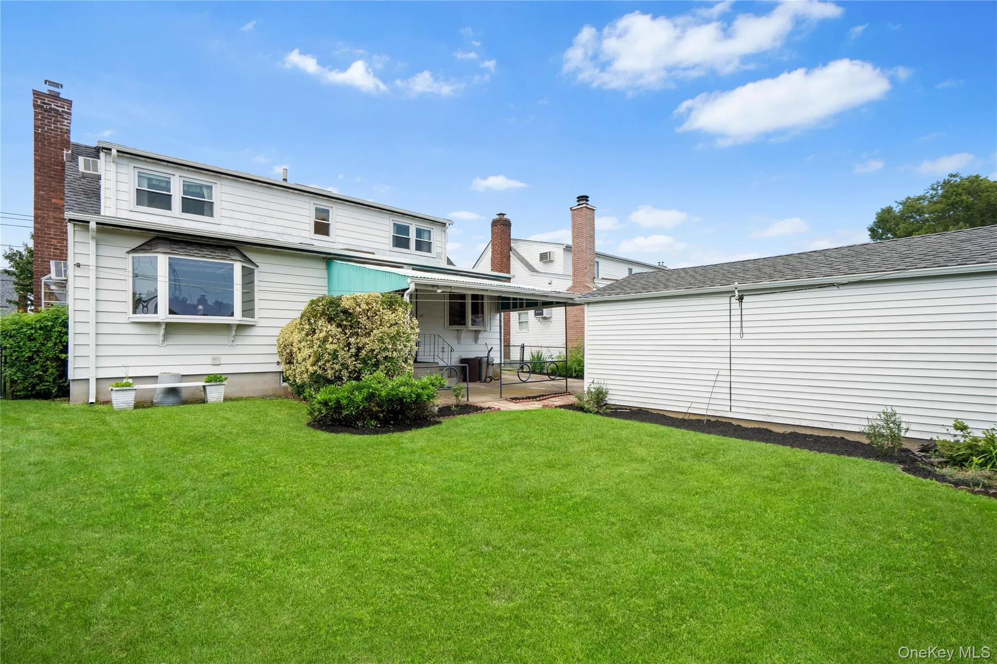 Expansive lawn area, white siding exterior, bay window, covered patio, and detached structure Expansive lawn area, white siding exterior, bay window, covered patio, and detached structure